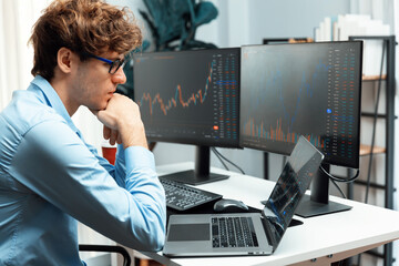 Working young business trader typing, focusing on laptop in market stock graph data investment in real time laptop in screens. at modern office, analyzing dynamic financial exchange rate. Gusher.