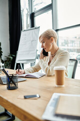 Middle-aged businesswoman with short hair multitasking at her modern desk, energetically chatting on her cell phone.