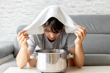 Teenage boy, child, doing steam inhalation at home to soothe and open nasal passages