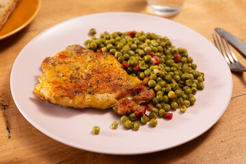 Fried boneless skinless chicken leg with green peas for garnish on plate
