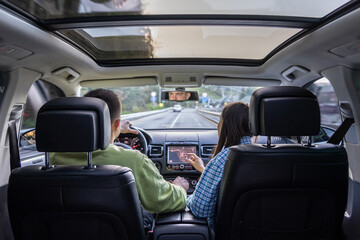 Rear back view from passenger seat of man and lady sitting inside car.