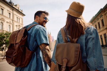 Happy traveler and his girlfriend walking through  town.