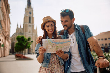 Happy woman and her boyfriends looking at map while exploring  city.