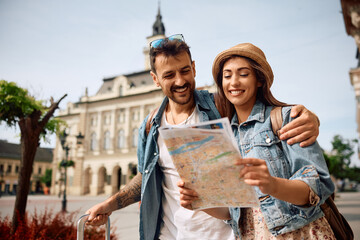 Happy couple enjoying in travel while exploring  map during their walk through  town.