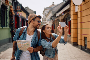 Happy tourist couple taking selfie while exploring city.