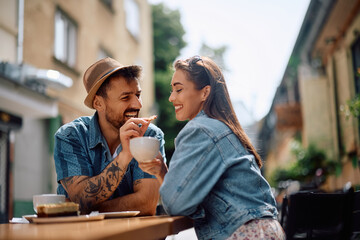 Happy couple sharing  cookie while drinking coffee in  café.
