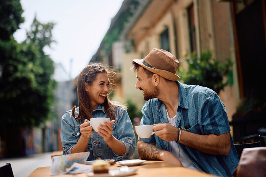 Happy couple of travelers drinking coffee in sidewalk café.