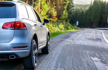 Fototapeta premium Car on the road in a forest in a mountainous area, the concept of a road trip.