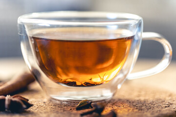 Close-up, glass cup of aromatic black tea on a blurred background.