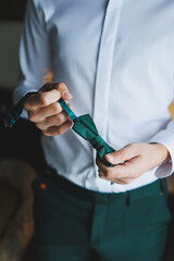 A man holds a stylish green butterfly in his hands. Bow tie for a stylish look.