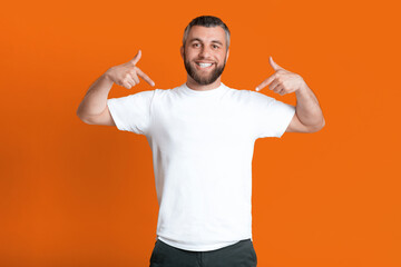 A man wearing a white shirt and black pants is standing in a casual pose, looking straight ahead. He appears relaxed and confident in his outfit choice.