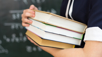 girl with stack of books, school education concept.