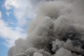 Toxic black smoke from fire against sky, burning plastic.