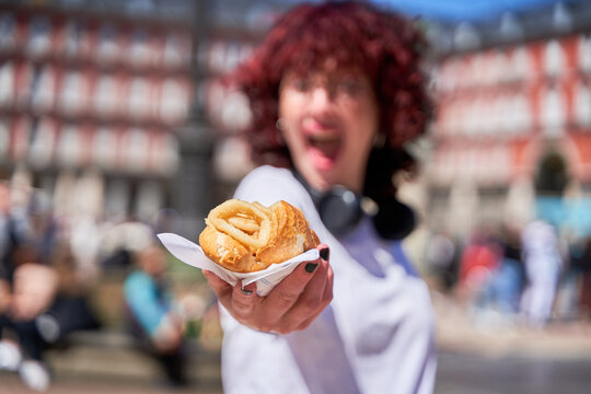 unrecognizable person holding a calamari sandwich in his hand, traditional Madrid food in the Plaza Mayor