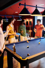Friends enjoying a friendly game of billiards in a dimly lit lounge.