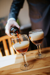 A close-up shot of a drink being poured into a glass, capturing the liquid in motion and highlighting the rich color and texture of the beverage.