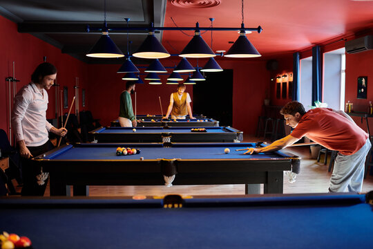 A group of friends playing billiards in a dimly lit pool hall.