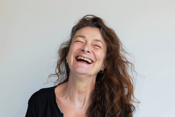 Portrait of a glad woman in her 50s laughing isolated in white background