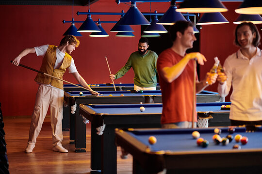Friends enjoying a casual billiards game at a dimly lit pool hall.