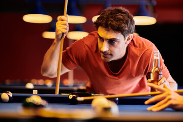 A man concentrates on his shot while playing billiards with friends.