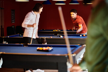 Friends play a game of billiards in a dimly lit bar, focusing on the game and enjoying their time...