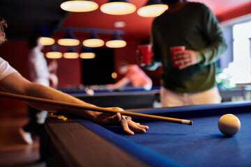 A close-up shot of a man playing billiards with friends in a casual setting.