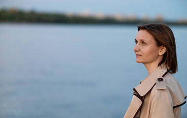 Young woman in formal clothes walking near grey wall outdoors, space for text