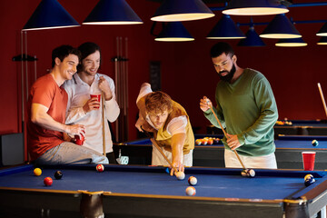 Friends play billiards in a dimly lit room, casually dressed and having fun.