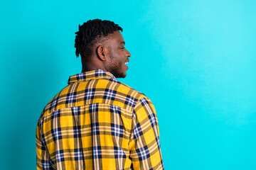 Fototapeta premium Back view photo of positive young man wear trendy plaid clothes empty space banner isolated on cyan color background