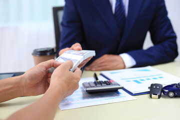 Car insurance documents or rental concept. A car broker helps his customers and explains the...