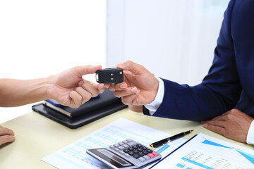 Car insurance documents or rental concept. A car broker helps his customers and explains the...