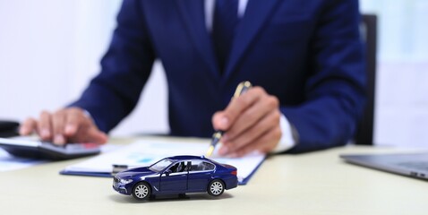 Car insurance documents or rental concept. A car broker helps his customers and explains the details of car contacts. Car keys. Buy or sell, sign.