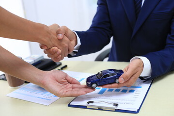 Car insurance documents or rental concept. A car broker helps his customers and explains the...