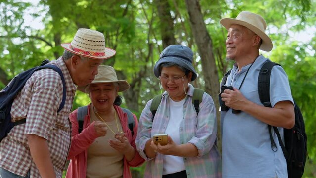Senior retirement activity, Group of happy senior friends on forest excursion looking Map and compass and GPS at a mobile phone during vacation, Backpack tourist travel outdoor holiday adventure