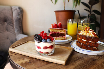 berry desserts and chocolate cake on a wooden table in the interior of the room