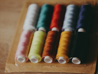 Multicolored sewing threads on paper bobbins and spools in blister packs. Threads for needlework,...