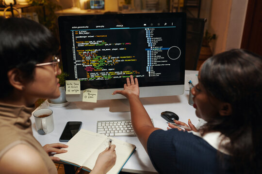 Team of developers discussing programming code on computer screen