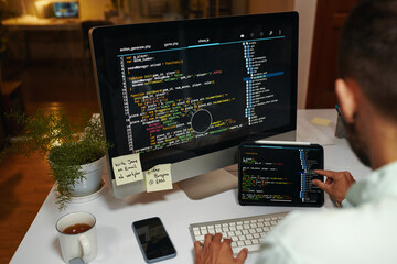 Developer busy with reviewing programming code on computer screen