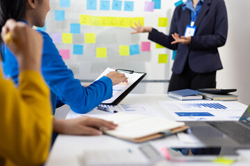 Businesswoman presenting to colleagues in conference room with charts and data