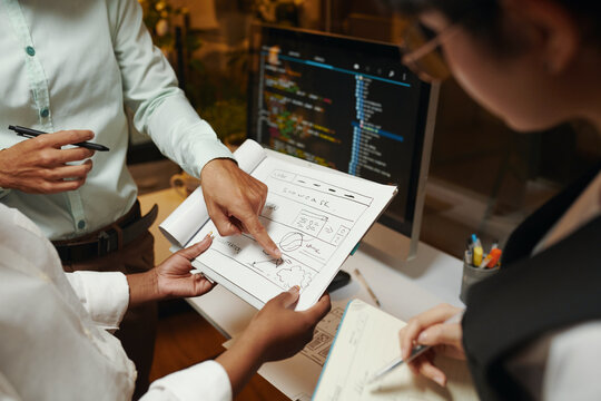 Closeup image of UI and UX designers discussing sketch of website design