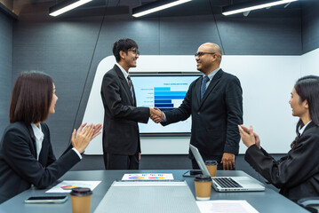 Happy Asian professional businessman shaking hands together greeting with businesswoman clapping hands for celebrating. Unity and diversity of position executive, manager and employee teamwork concept