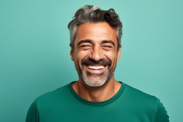 
Portrait photo of a happy Middle Eastern man, 45 years old, winking on a pastel teal background