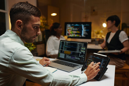 Developer checking programming code on tablet and laptop