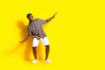 Photo of positive cool man wear trendy clothes look empty space isolated on yellow color background