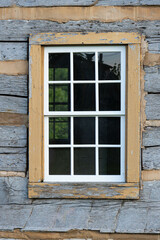 Looking at a window on an old pioneer log home from the outside.