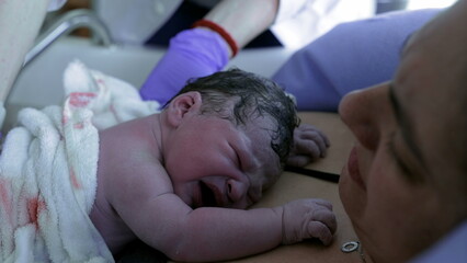 Childbirth moment of newborn crying on mother's chest feeling her skin right after birth, doctor...
