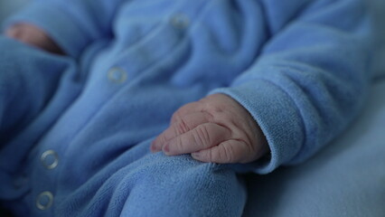 Close-up of a newborn baby's hand in a cozy outfit, highlighting delicate features and soft skin, symbolizing new life, parental love, and the tender moments of early infancy