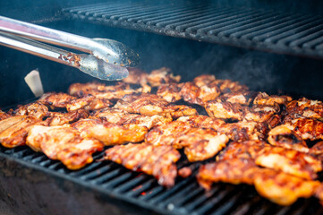 Grilled chicken on a barbecue, smoke rising.