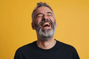 Obraz premium Portrait of a joyful man in his 40s laughing over pastel yellow background
