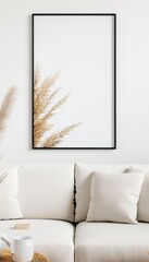 Minimalist living room with a beige sofa, white cushions, and a black-framed wall picture featuring dried pampas grass.